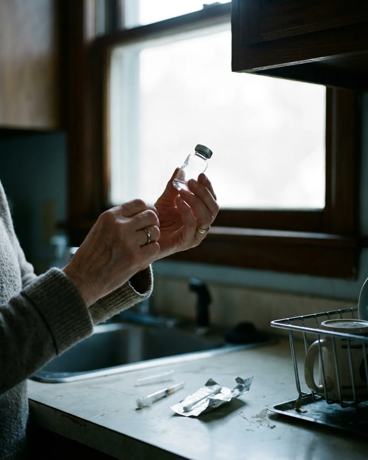 Hands holding a small unlabelled vial up to window light.